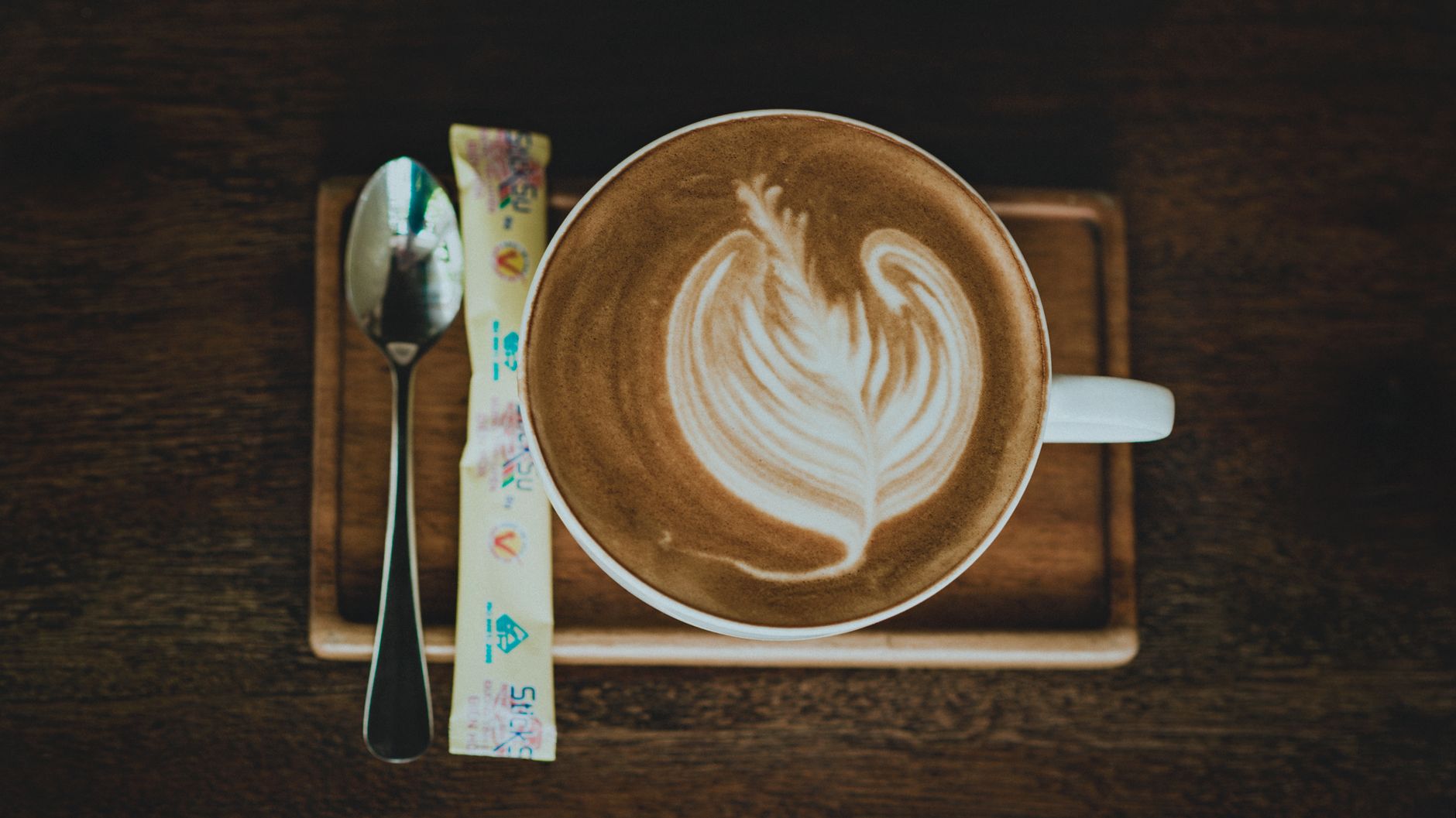 Small tray holding sugar, spoons, and a creamer beside a coffee maker