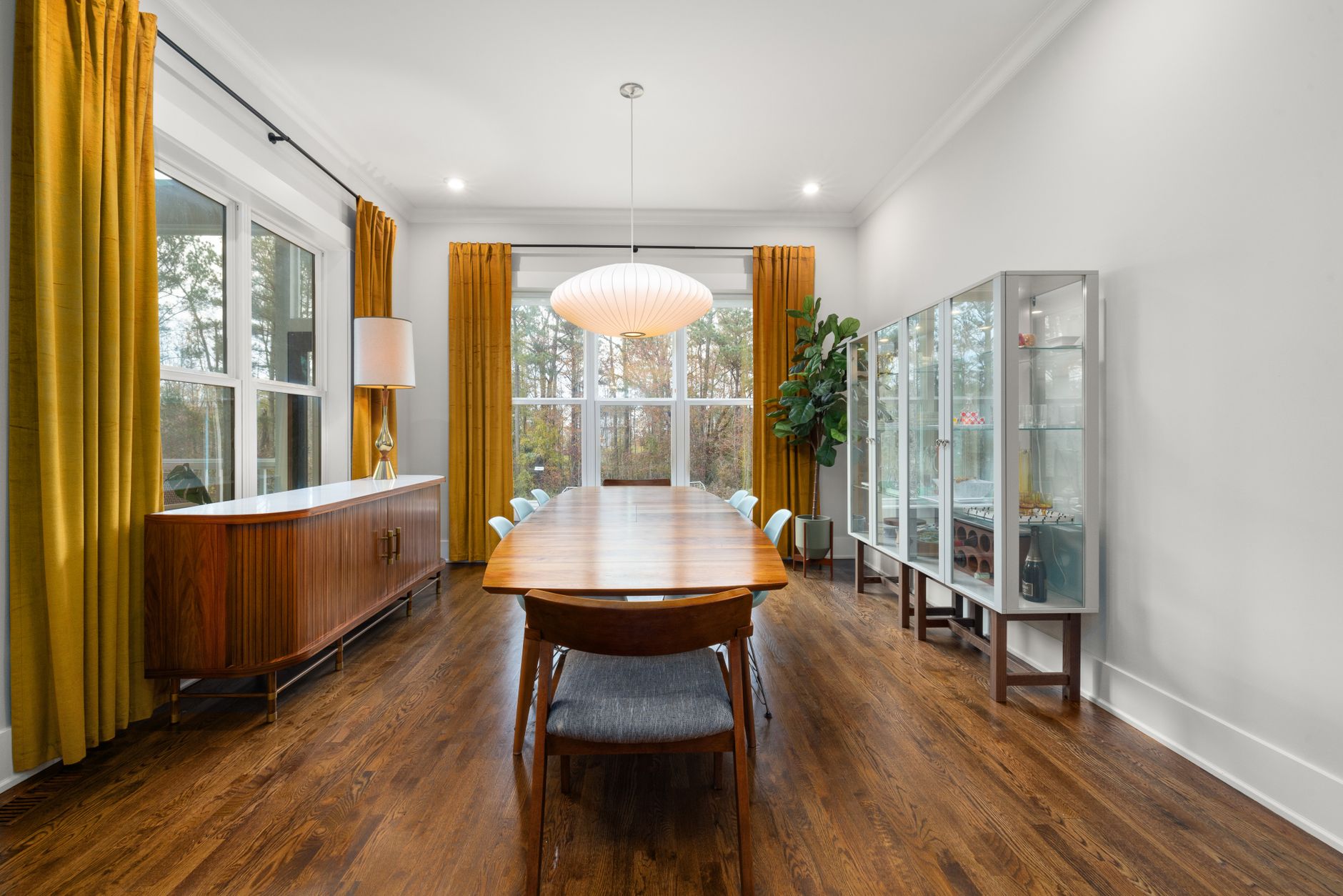 Low walnut credenza with sliding doors set up as a coffee bar against a plaster wall