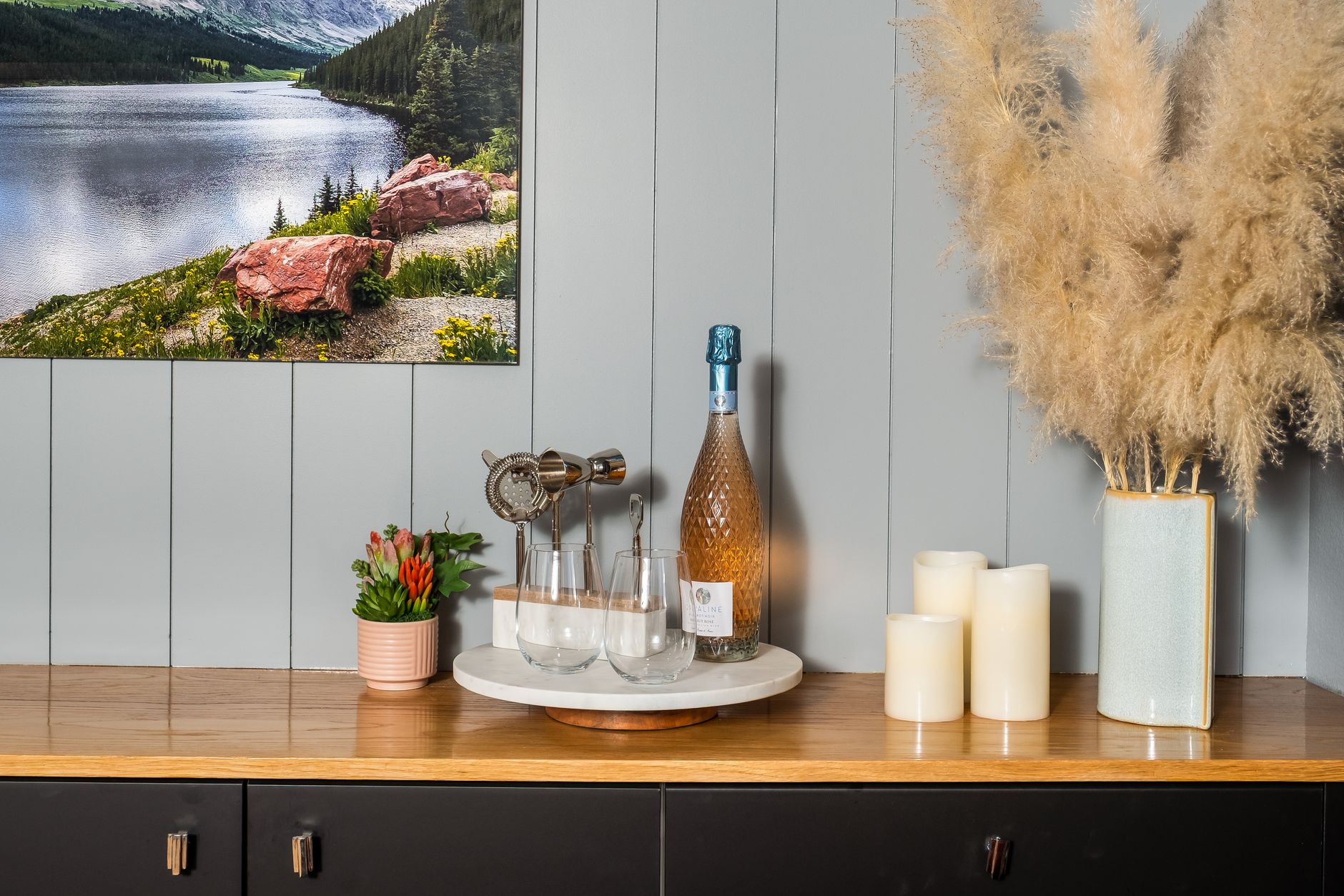 A dark wood dining room sideboard set up with a tray, carafe and glassware