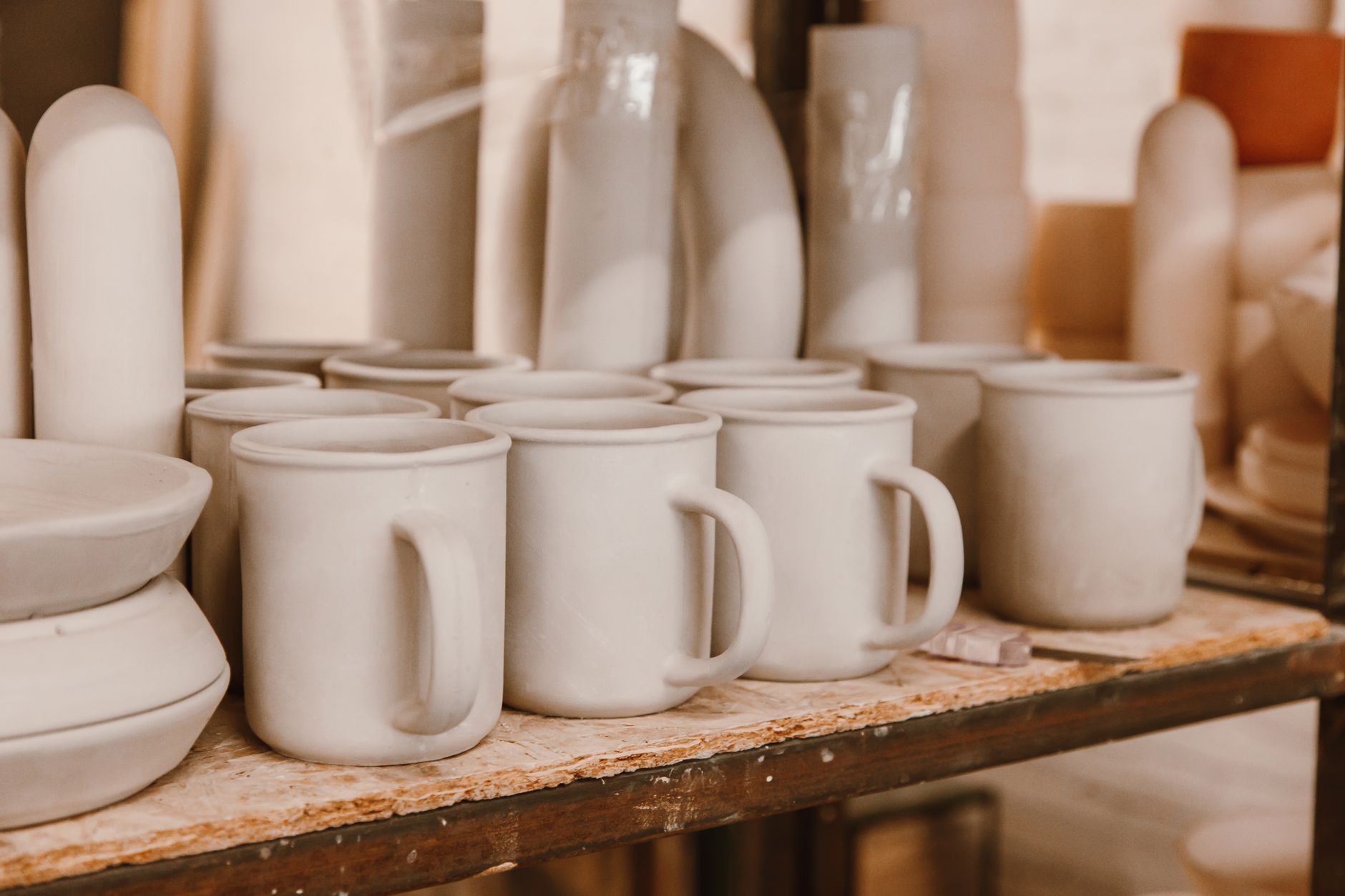 Speckled stoneware mugs stacked two deep on a wooden shelf